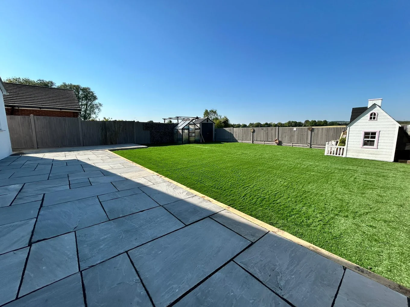 Large lawn and stone patio in a bright open family garden